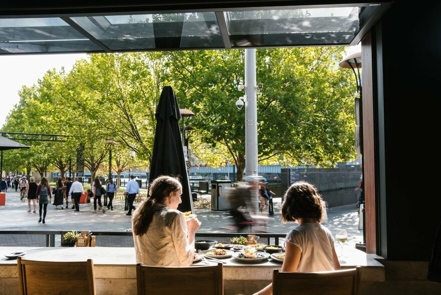 Two women enjoying a meal together overlooking the Southbank promenade in Melbourne.