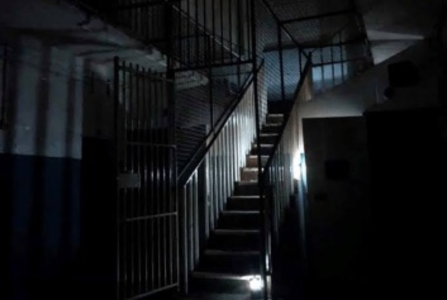 Spooky staircase lit by lamps in a dark hallway.