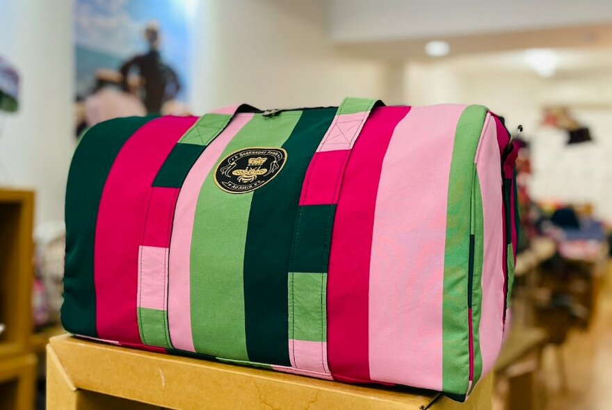 Close-up of pink and green striped bag, retail space visible at rear.