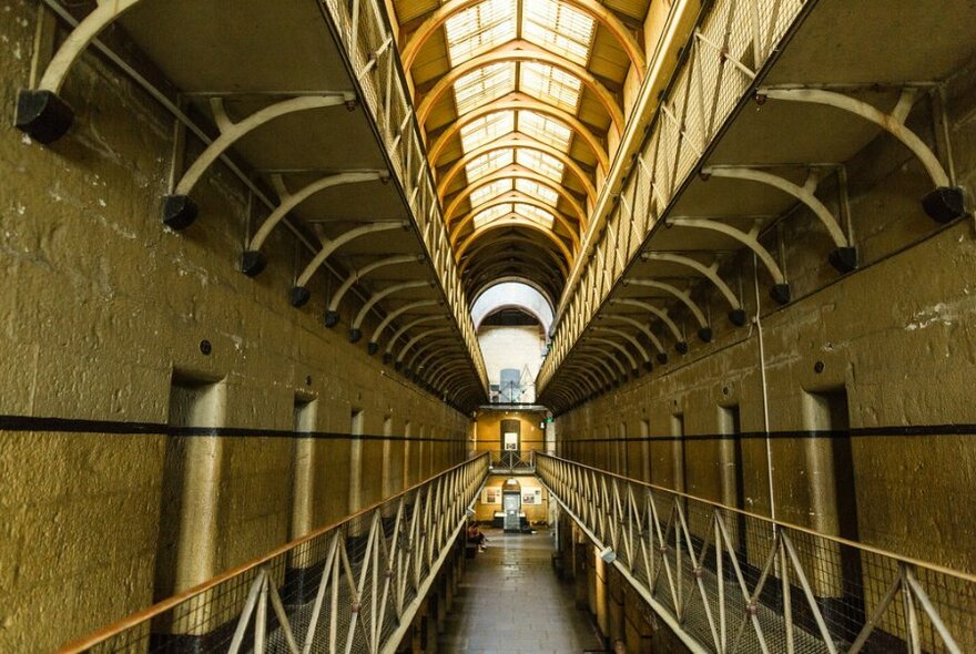 A long, narrow gaol with walkways and cells on either side.