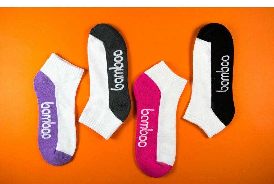 Four short socks with 'bamboo' written on sole on orange background.
