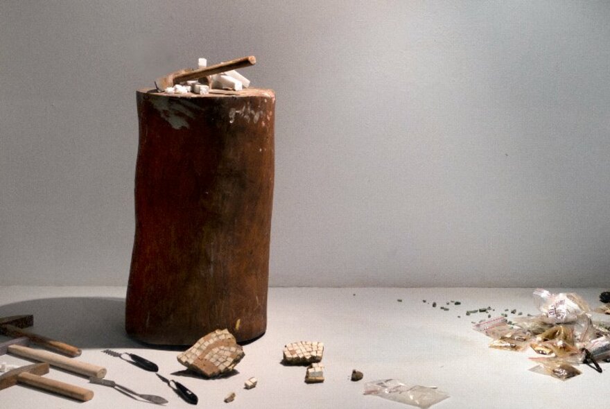 An artwork installation showcasing reclaimed, discarded materials including a rusted cylinder. 