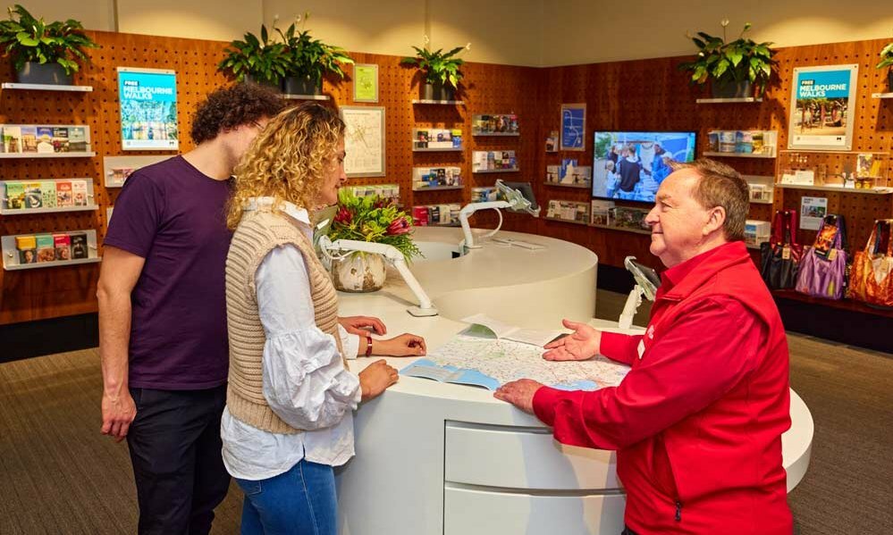 A volunteer in a tourist info centre talking to a pair of visitors