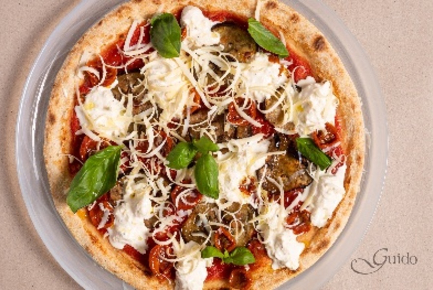 Pizza with tomato base, mozzarella cheese topping and basil leaves on it.
