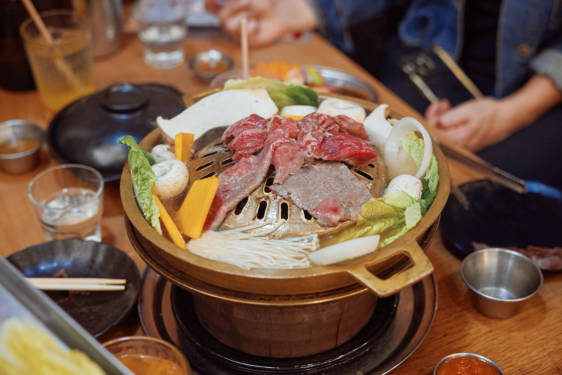 A gold grill with meat and veggies cooking. 