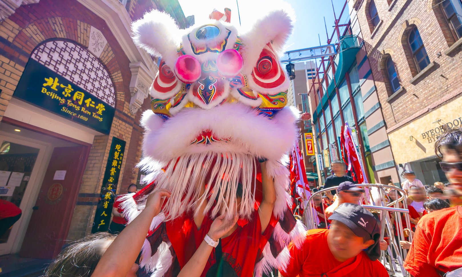 A lion dance performer surrounded by crowds.