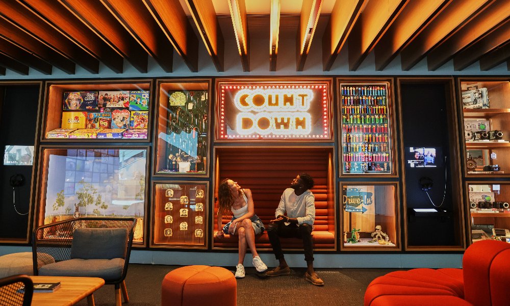 A couple in a gallery looking up at a sign that says count down.