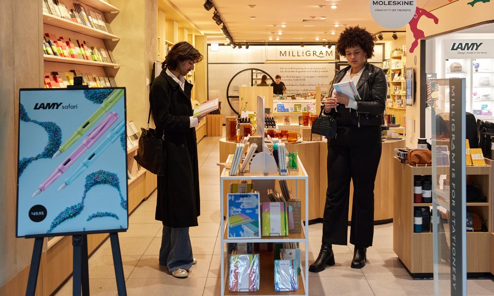 Two friends are looking at notebooks in a shop.
