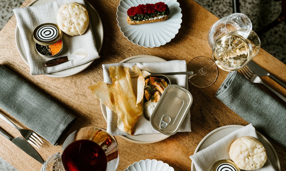 A table set with tinned fish, wine and other bar snacks. 