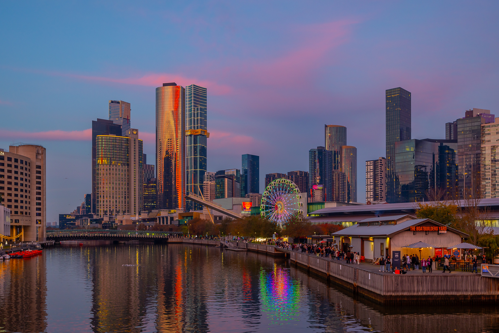 Pink sunset clouds over the city skyline and a Ferris wheel.