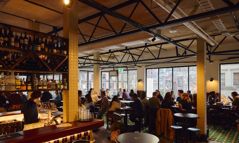 A crowd of people are drinking and eating a pub