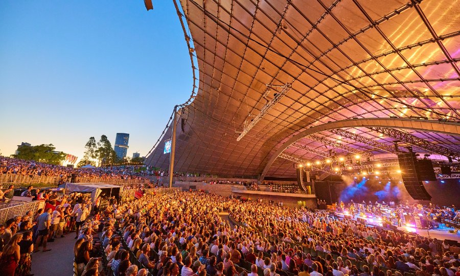 Large crowd of people watching a concert at the Sidney Myer Music Bowl. 