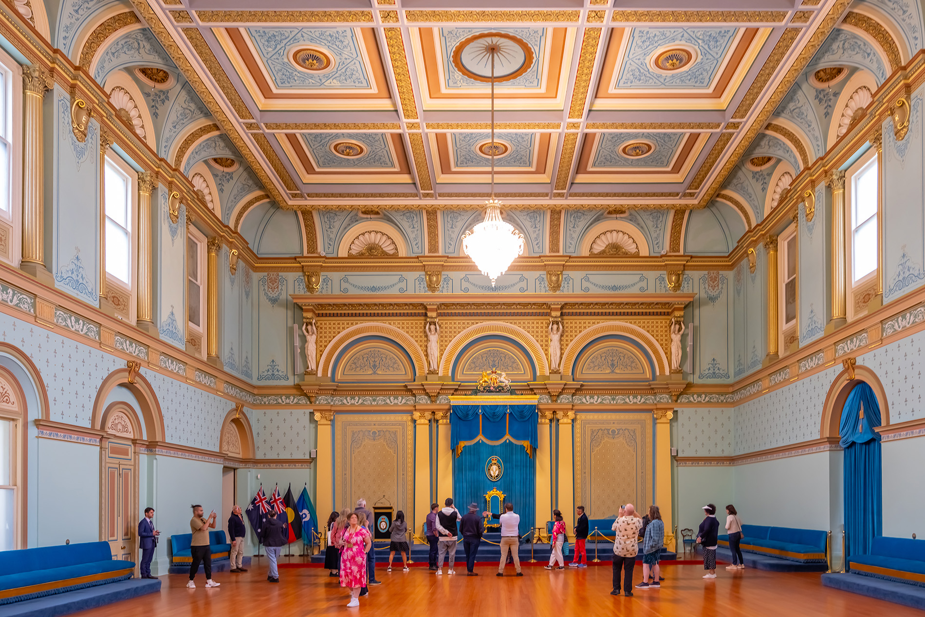 Crowds exploring an ornate government house room styled in blue and gold.
