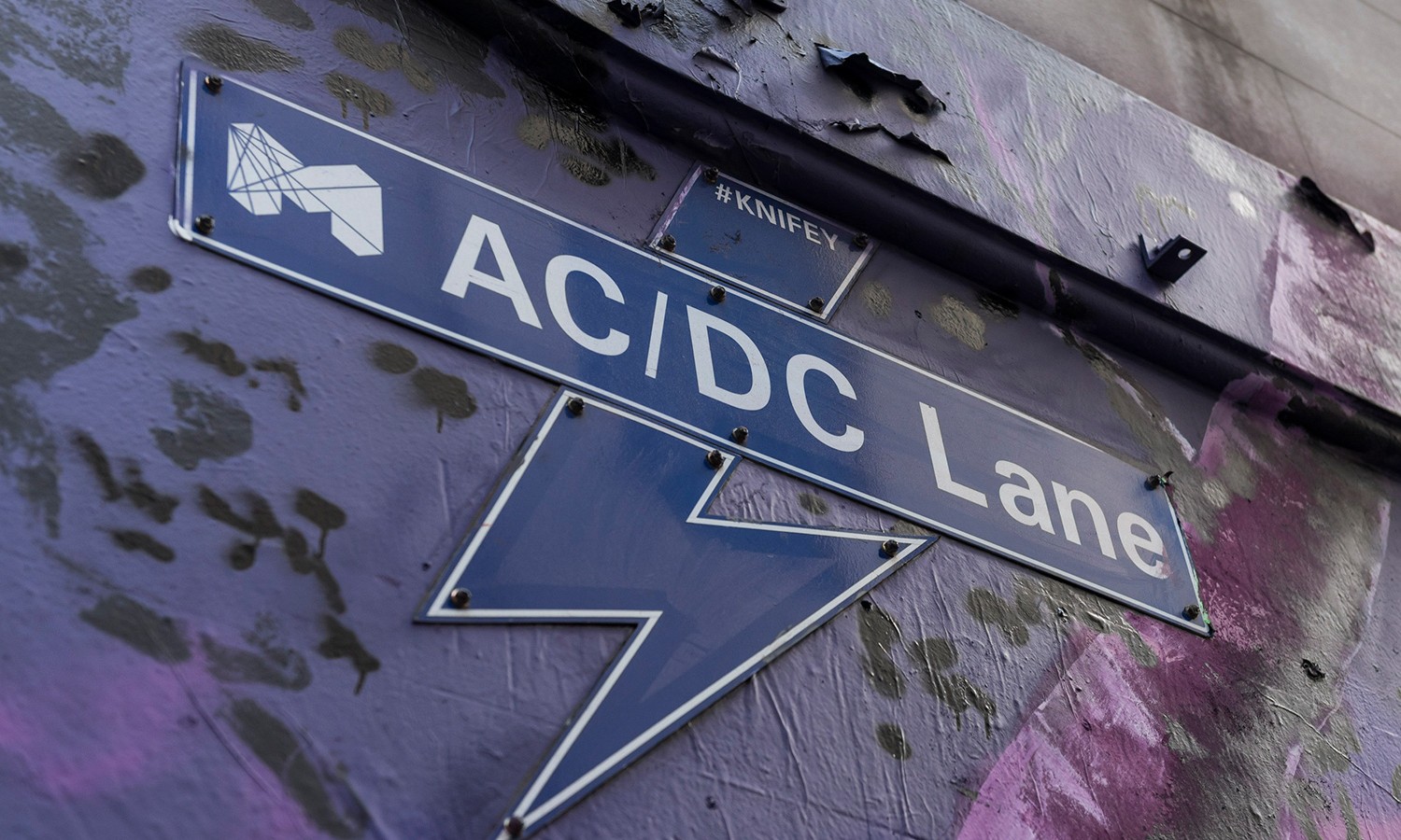 Lighting bolt sign for AC/DC Lane on the side of a wall. 