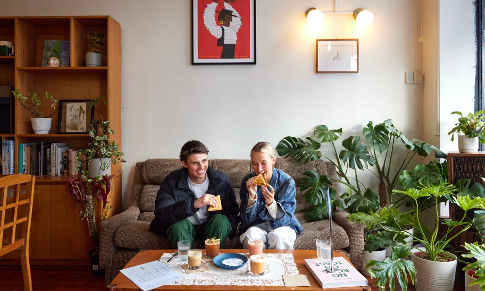 Two people enjoying brunch on a couch.