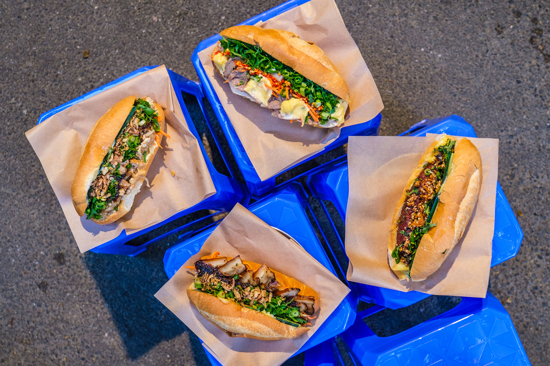 Four different flavoured banh mis on small blue stools.