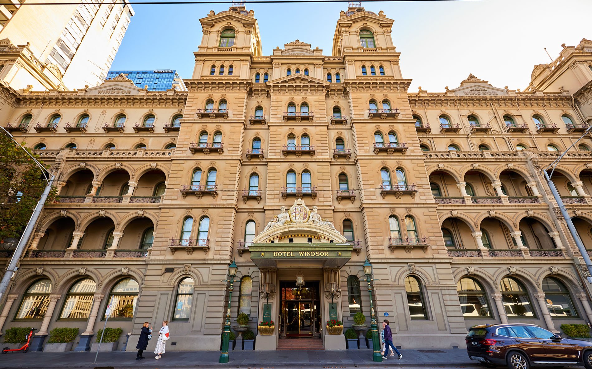 People walking into a grand seven-storey hotel in the city.