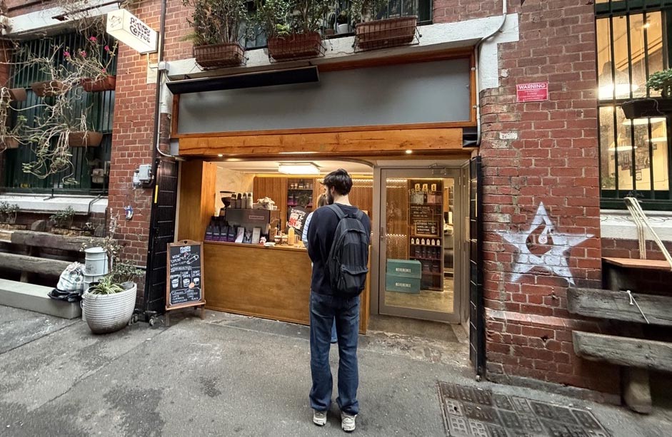 A man ordering from a  laneway coffee window. 