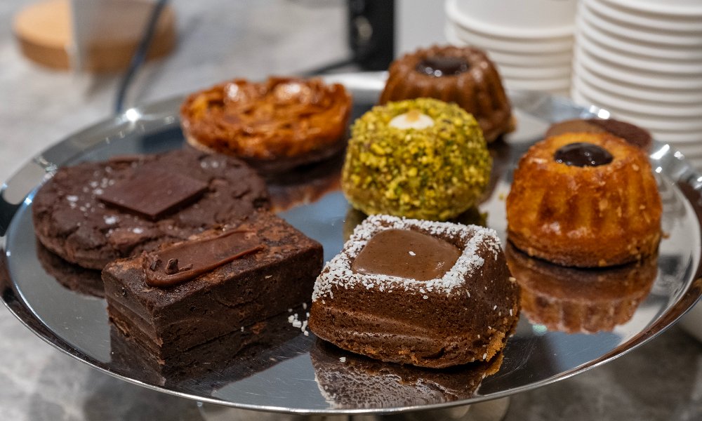 A selection of chocolate cakes, pastries, brownies and cookies on a tray.