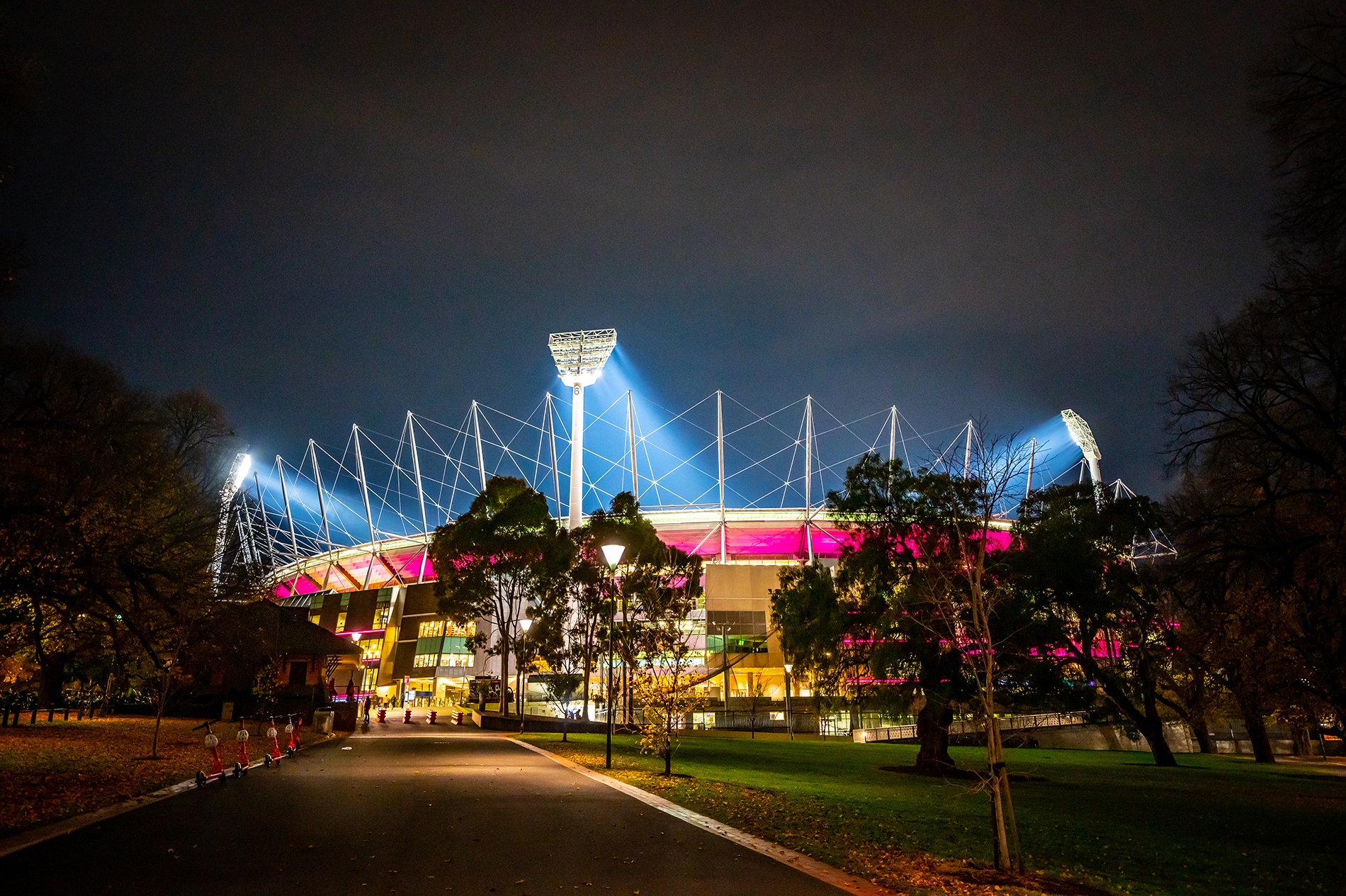 MCG football stadium lit up pink at night.