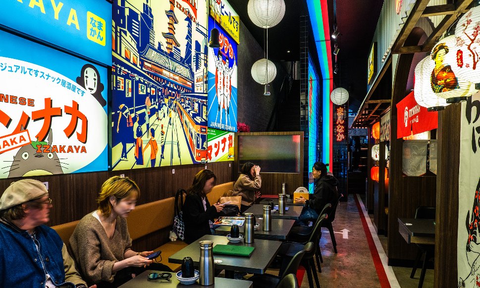 Inside a Japanese diner with glowing posters on the walls and lanterns hanging from above. 