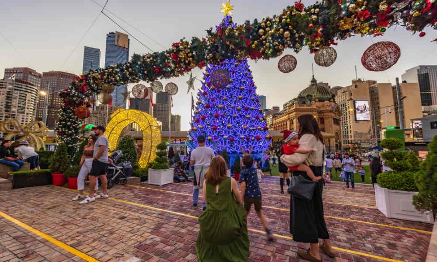 A family with kids at a Christmas event with a large glowing Christmas tree.