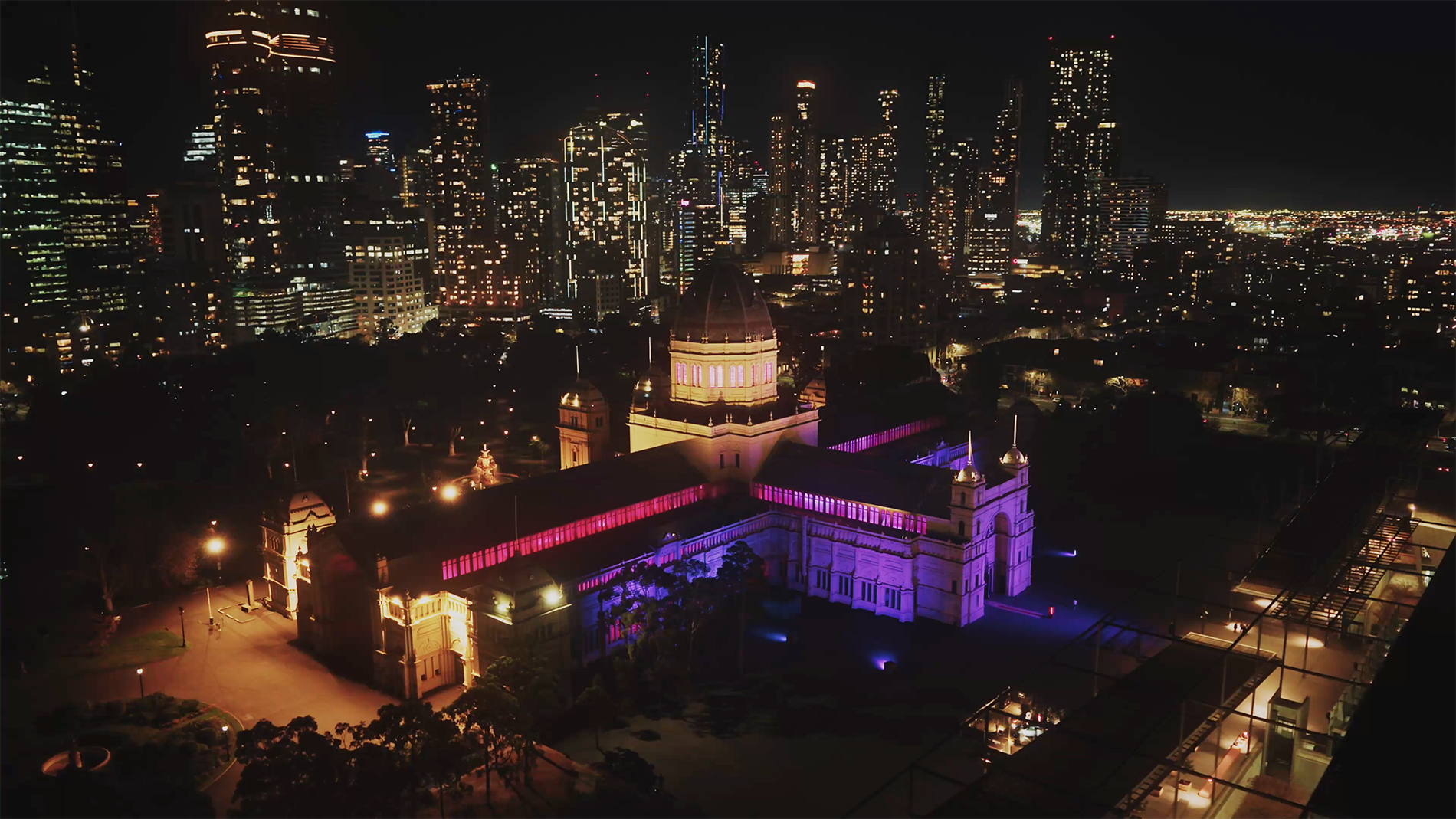A large building lit up purple in the city at night.