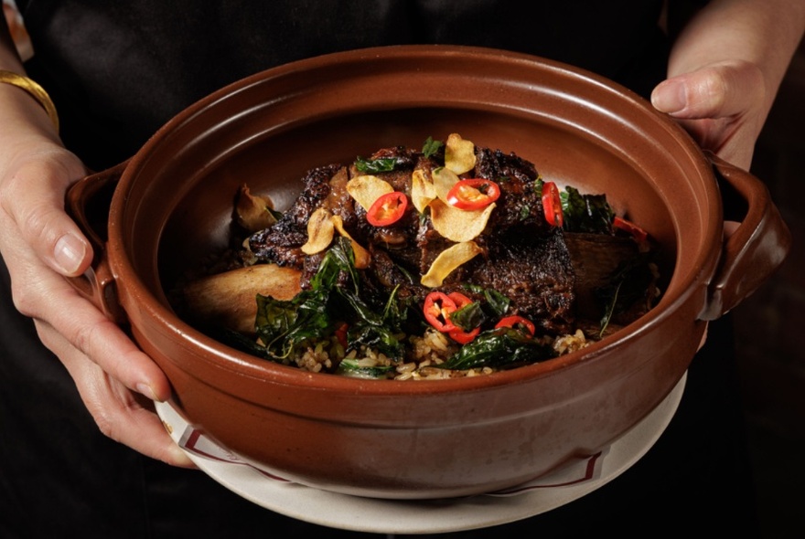 An Asian-inspired curry dish presented in a brown earthenware pot.