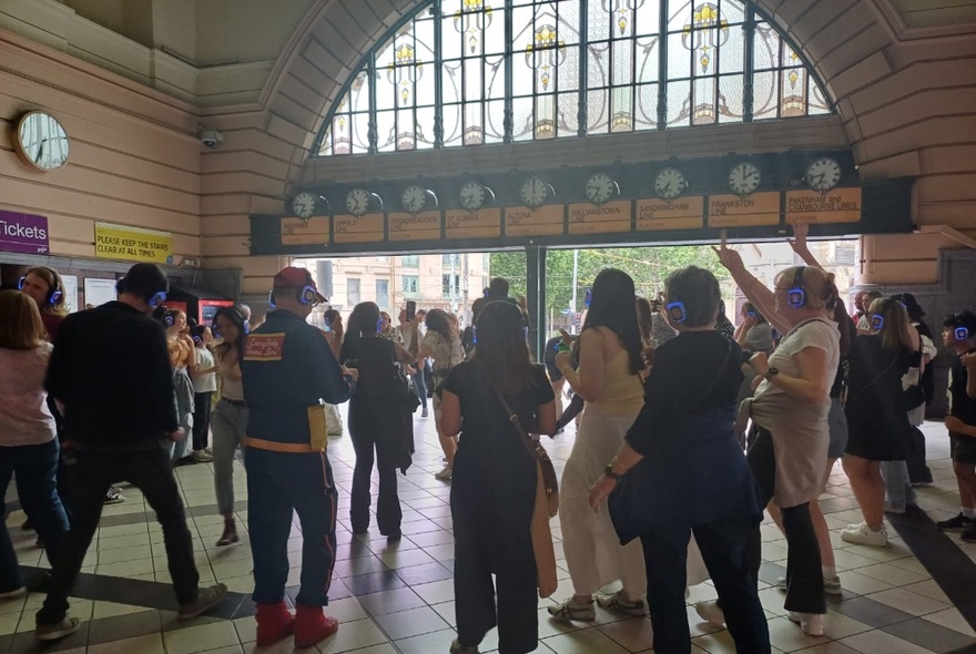 Group of disco walking tour participants dancing under the clocks at Flinders St Station.