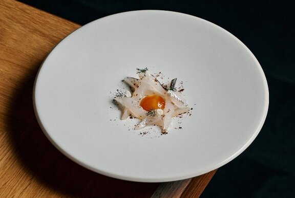 White plate with delicately arranged food in the centre.