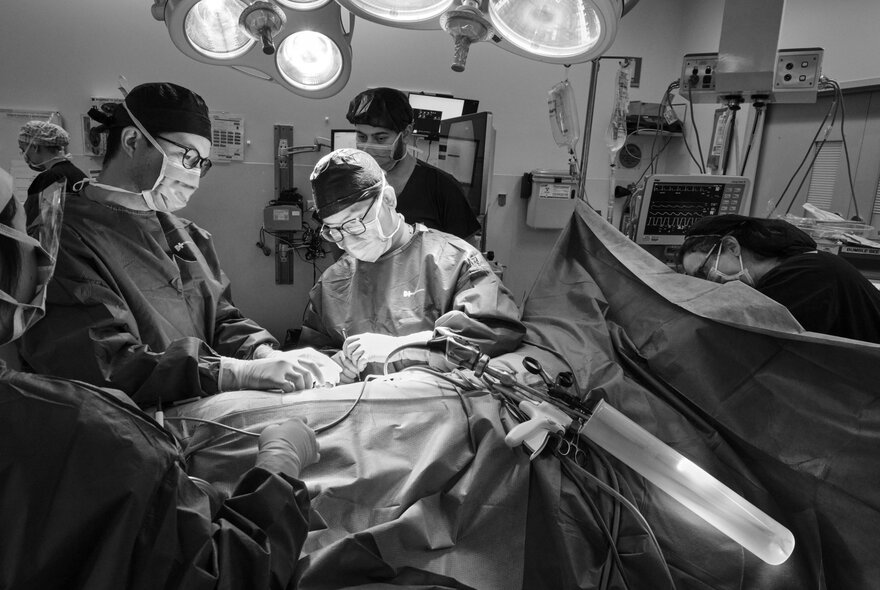 Doctors performing surgery surrounded by lights and equipment.