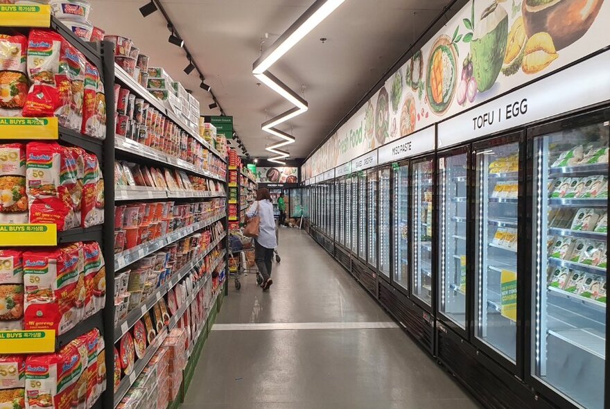 Supermarket aisles with stacked prodcuts and long line of refrigerators.