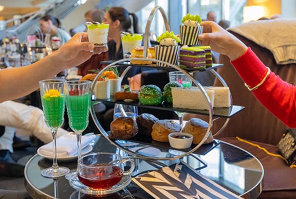 A tiered silver high tea tray with green Beetlejuice character themed treats.