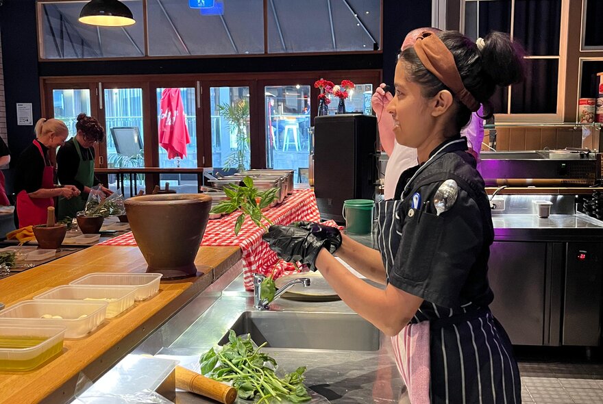 A chef demonstrating how to make pesto at an Italian restaurant's cooking class.
