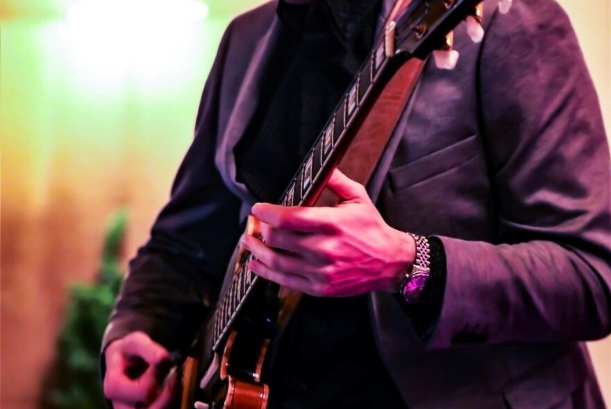 Close up of the torso of a man playing a guitar. 