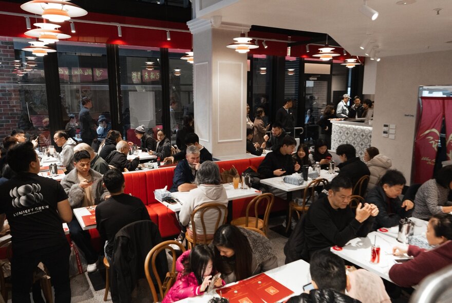 Patrons eating in a Singaporean restaurant with red decor.