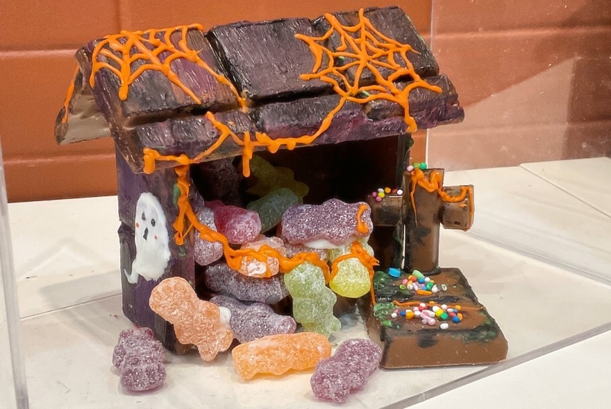 Edible house made of chocolate with gummy spook bears and orange spiderwebs.