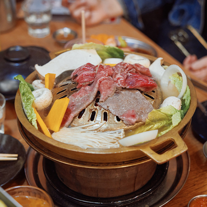 A gold grill with meat and veggies cooking. 