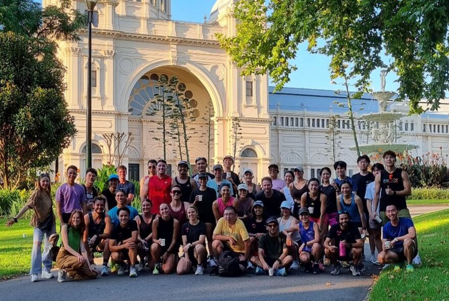 Large group of people posed outside Exhibition Building in the sunshine.