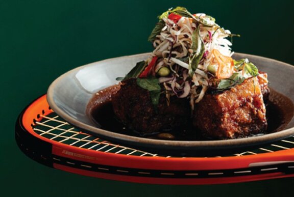 A plate of food balancing on the strings of a tennis racquet.