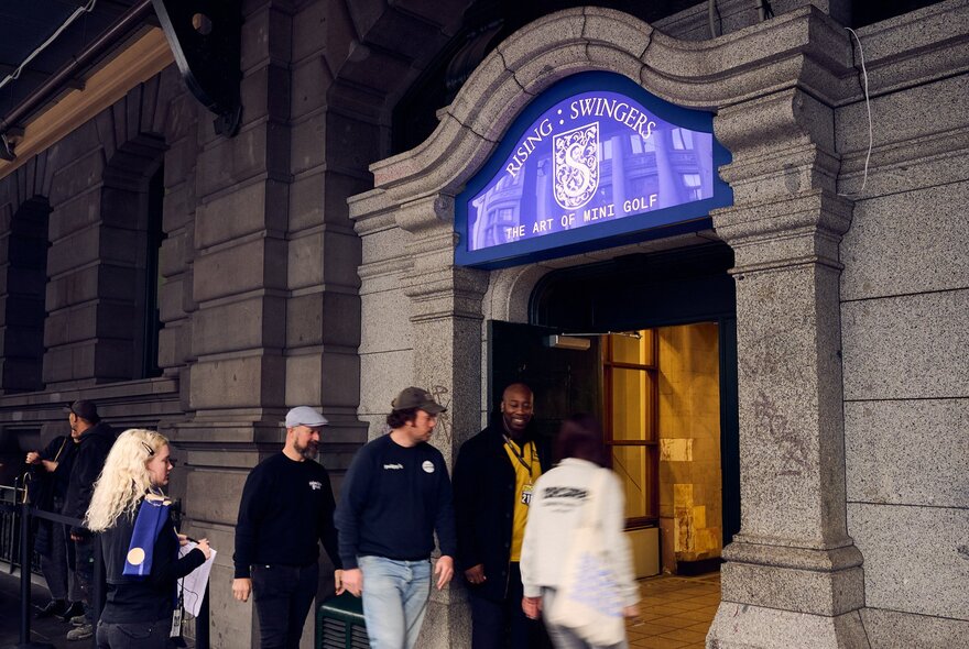 People entering an exhibition through a doorway with elaborate stonework. 