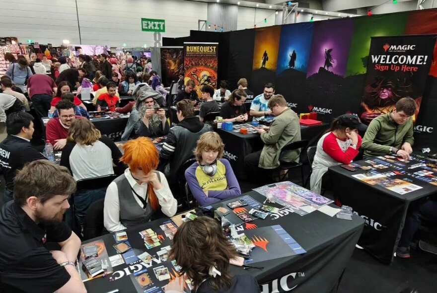 People participating in gaming at tables at Comic-Con.