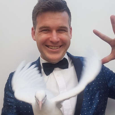 Magician Ashley appearing on stage with one of his white doves.