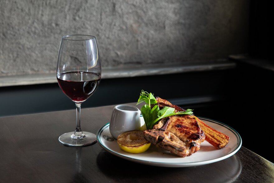 A plate of food on a table, with a glass of red wine next to it.