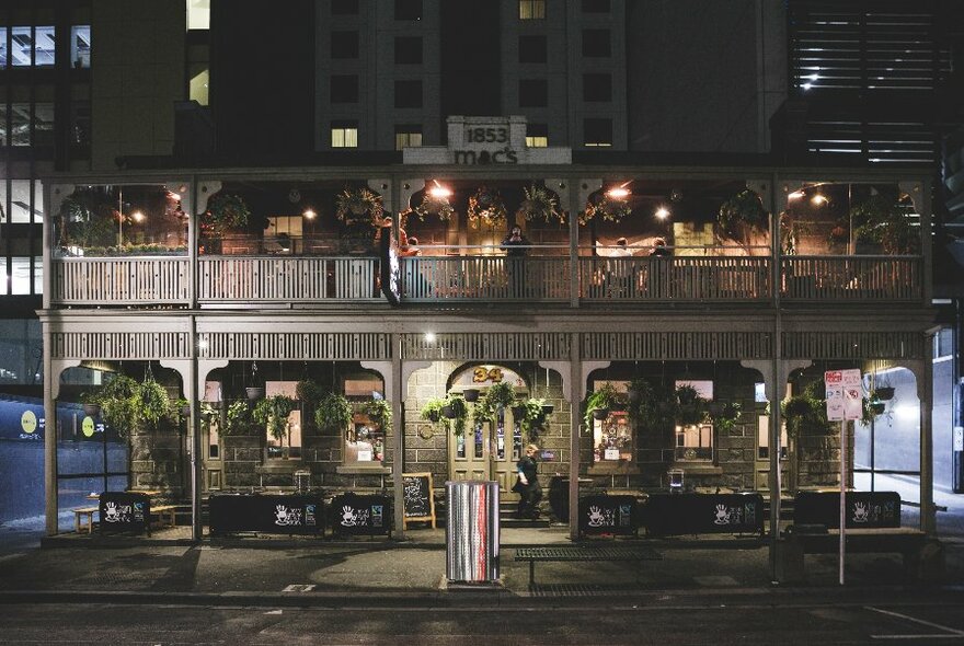 Exterior of Captain Melville at night with lacework colonial balcony and bluestone walls.