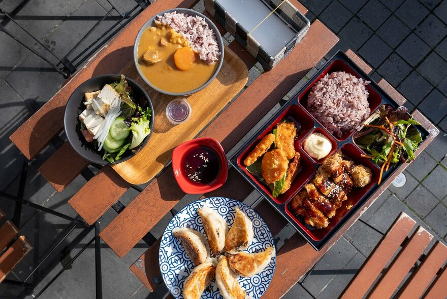 A table set with Japanese dishes included curry, gyoza and fried chicken. 