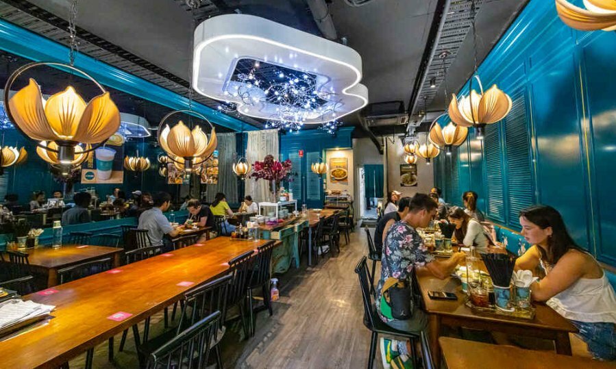 The inside of a restaurants with blue walls, lotus-shaped light fixtures and a large white light feature in the centre of the ceiling. 