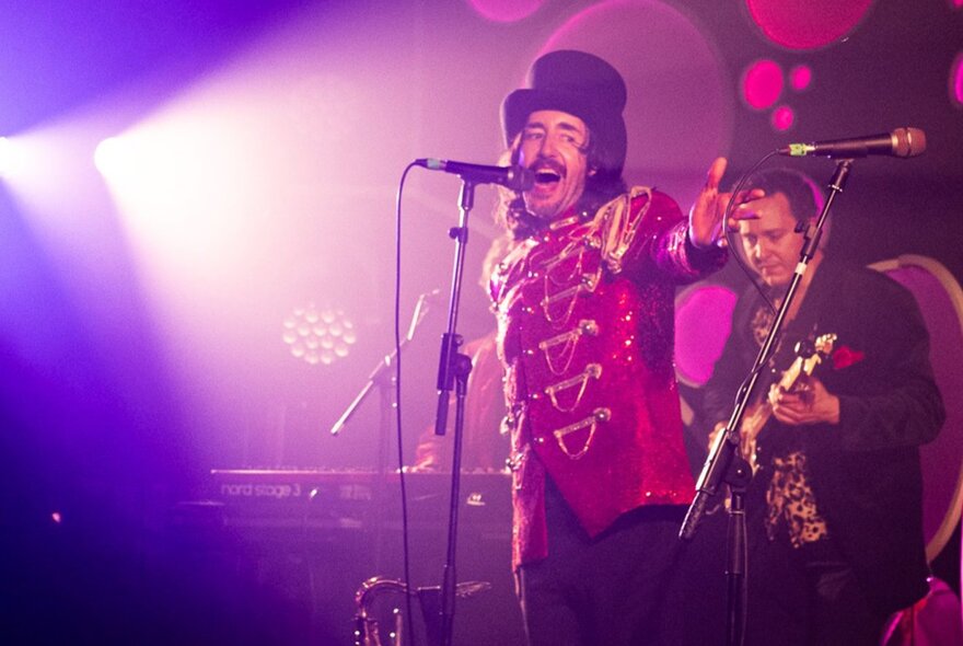 A singer in a band on stage, wearing a Nutcracker-inspired jacket and top hat.