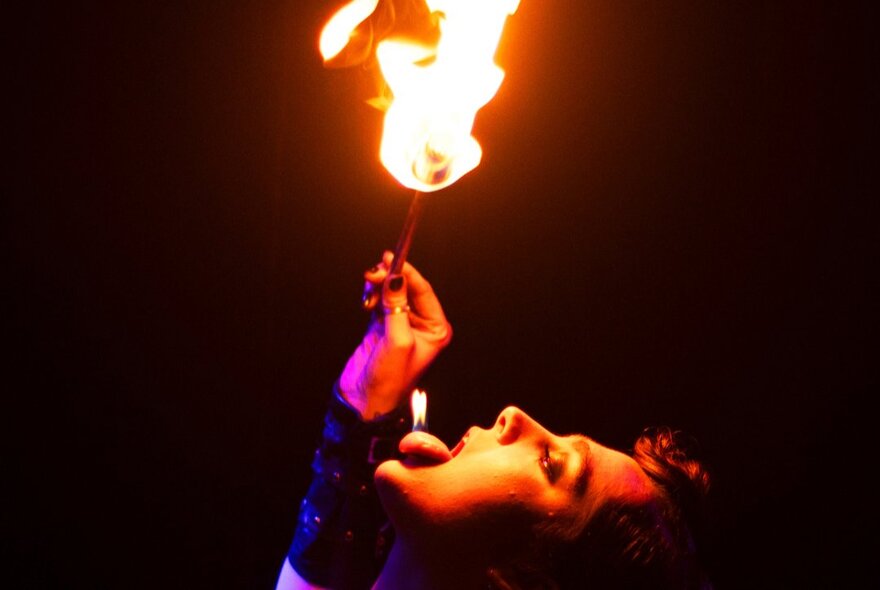 Performer breathing fire with head tilted at an angle.