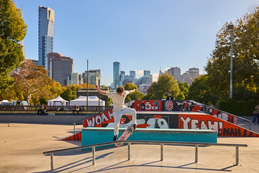 A man doing a skateboard trick in a Melbourne skate park on a sunny day.